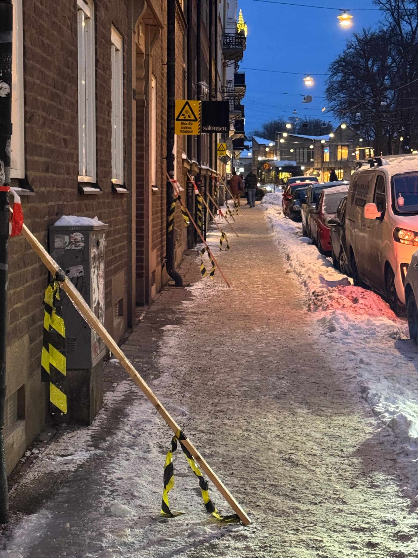 Avspärrad trottoar med varningsband på grund av risk för istappar